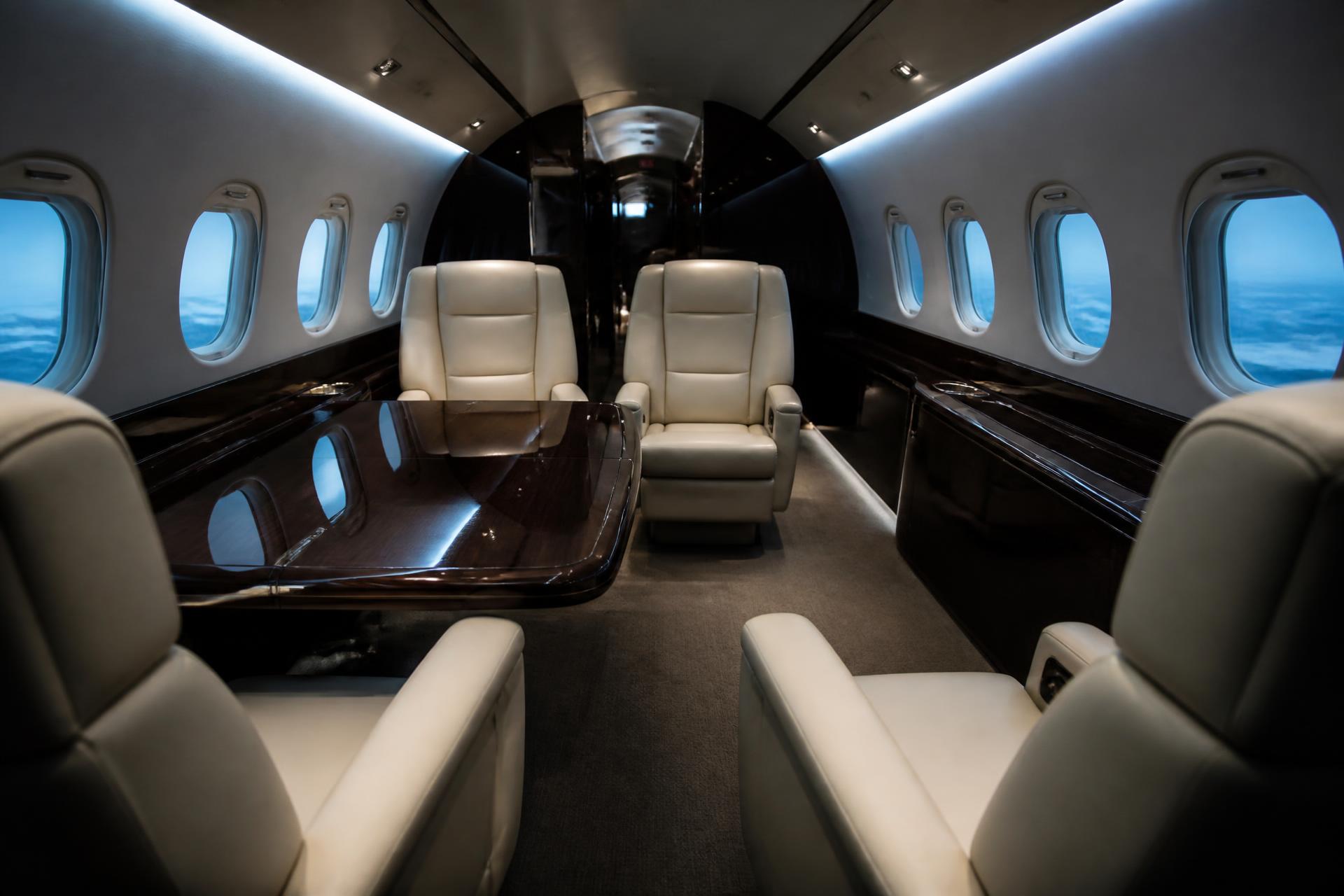 Interior of a long-range private jet cabin with cream leather club seats
